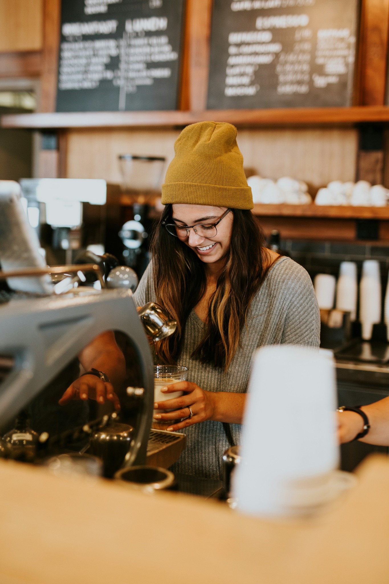 An independent café owner preparing a drink behind the counter